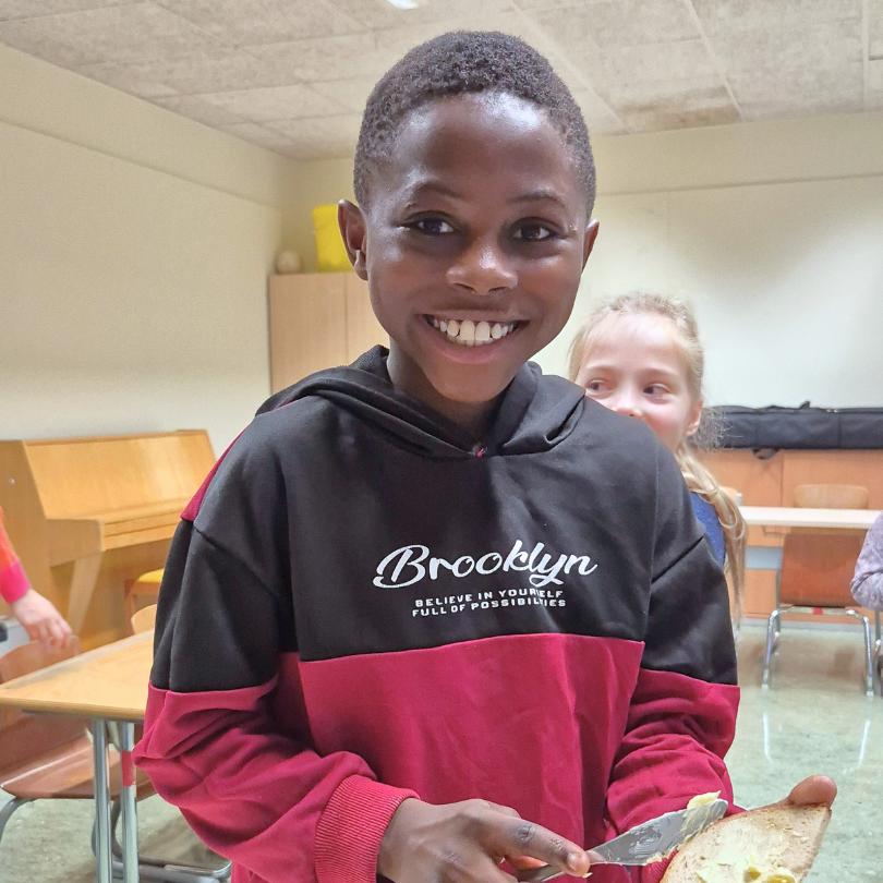 Klinton steht im Frühstücksklub der Schule im Olympiadorf in München und schmiert isch ein Butterbrot.