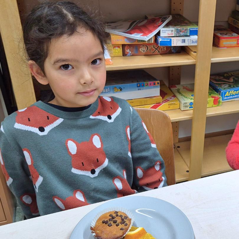 Ein Mädchen, Liselotte, 7 Jahre, sitzt im Frühstücksklub der Schule im Olympiadorf in München vor einem Teller mit Muffin und Obst.