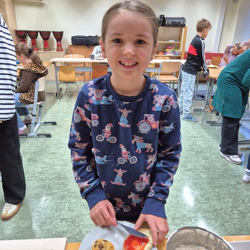 Ein Mädchen, Naomi, 8 Jahre, bereitet im Frühstücksklub der Schule im Olympiadorf in München ein Brötchen mit Marmelade zu.