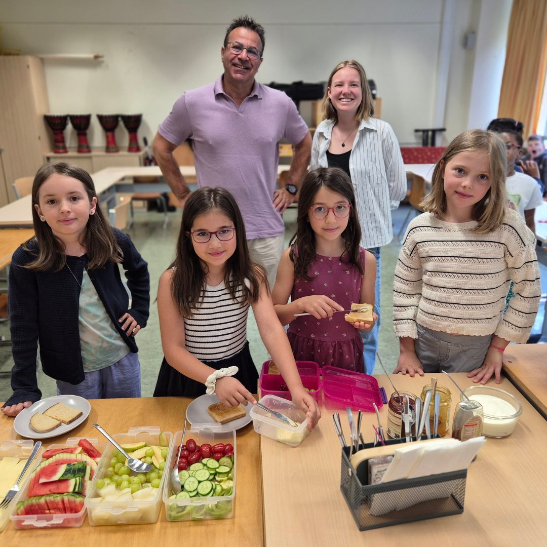 Kinder bereiten gemeinsam mit Mitarbeitenden der Deutschen Lebensbrücke und dem Spender acterience im Frühstücksklub München ein gesundes Frühstück zu.