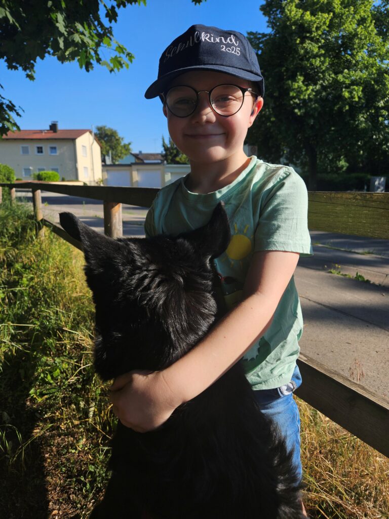 Silas hält einen großen schwarzen Hund im Arm – Nähe zu Tieren kann dem siebenjährigen Jungen Ruhe und emotionalen Halt schenken.